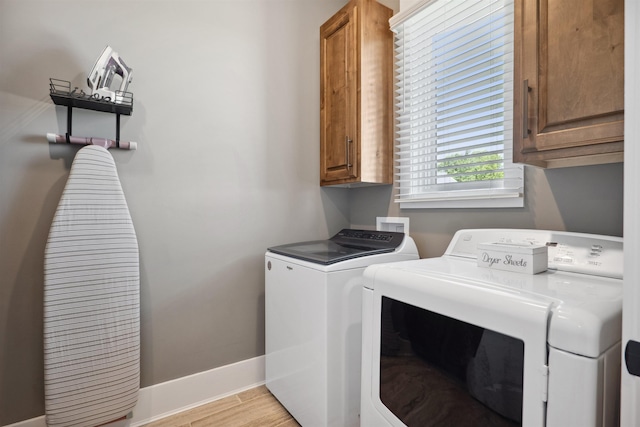 2059 Sloan Lake Dr, Jonesboro, AR 72404 - laundry area featuring cabinet space, washing machine and dryer, baseboards, and light wood-style flooring