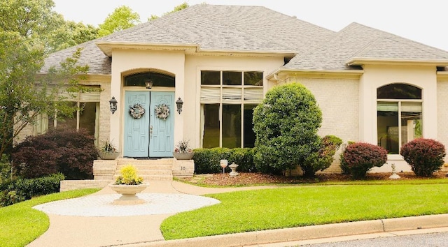 10 Calumet Rd, Little Rock, AR 72223 - view of exterior entry featuring a yard, a shingled roof, and stucco siding