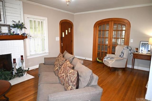 605 School St, Sheridan, AR 72150 - living room featuring arched walkways, crown molding, wood finished floors, a brick fireplace, and baseboards