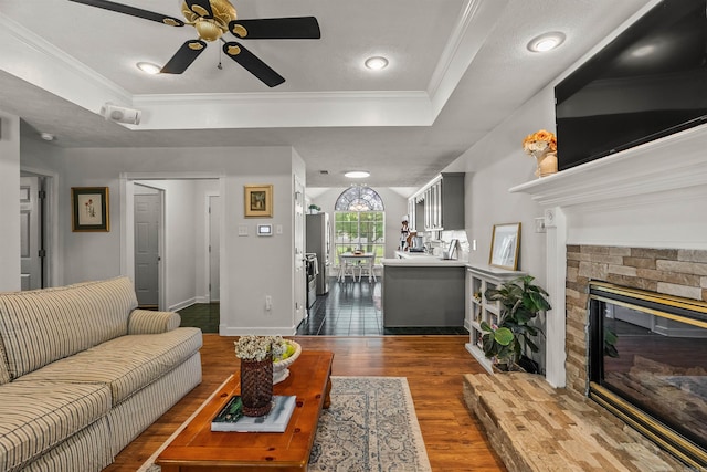 1050 Santa Fe Trl, Conway, AR 72034 - living room featuring a tray ceiling, a fireplace, ceiling fan, dark wood-style flooring, and ornamental molding
