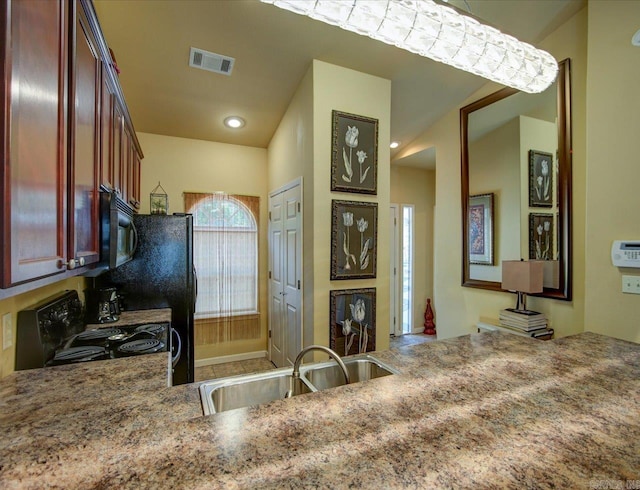kitchen with a sink, black microwave, range with electric stovetop, and light stone countertops