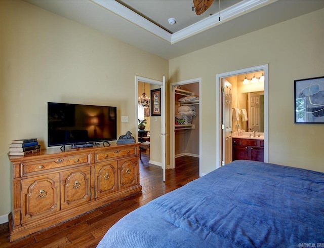 bedroom featuring dark wood-style floors, a walk in closet, ensuite bath, a sink, and a closet