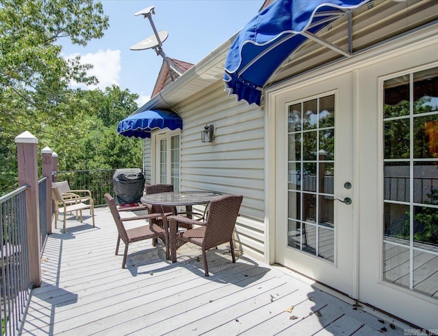 wooden terrace with outdoor dining area and french doors