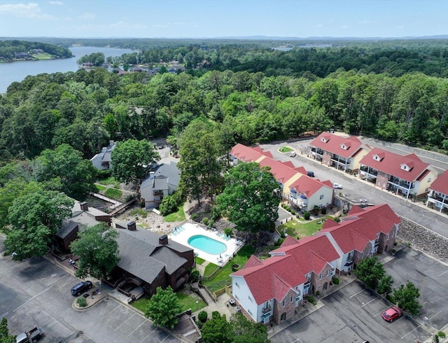 bird's eye view of a forest, a nearby body of water, and a pool area