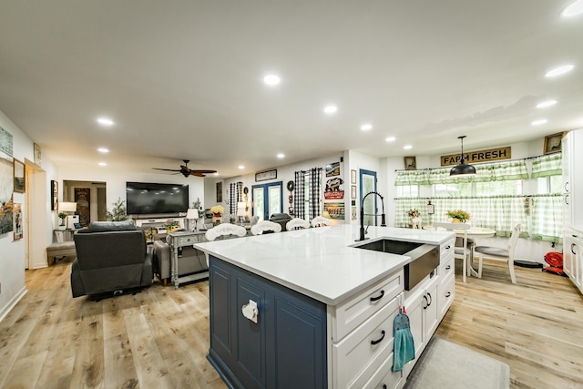 100 Hidgen Rdg, Higden, AR 72067 - kitchen featuring a sink, an island with sink, open floor plan, light wood-style floors, and white cabinets