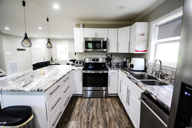 kitchen with appliances with stainless steel finishes, a sink, a peninsula, white cabinetry, and ornamental molding