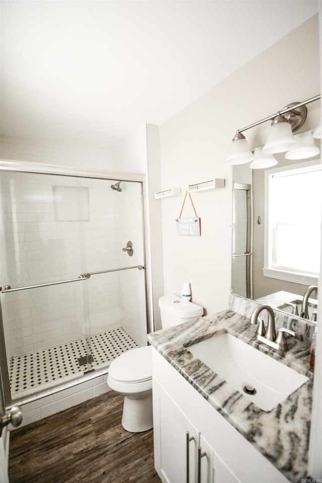 bathroom featuring vanity, a shower stall, toilet, and wood finished floors
