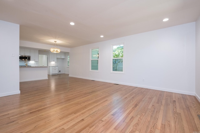 700 N Taylor St, Little Rock, AR 72205 - unfurnished living room with light wood-type flooring, recessed lighting, baseboards, and a chandelier