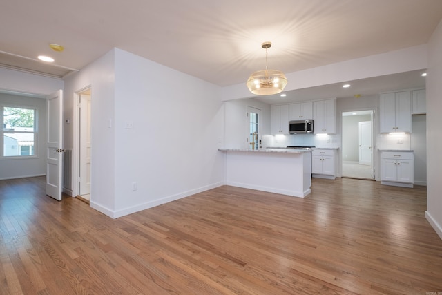 700 N Taylor St, Little Rock, AR 72205 - kitchen with stainless steel microwave, light wood-type flooring, white cabinetry, a peninsula, and baseboards