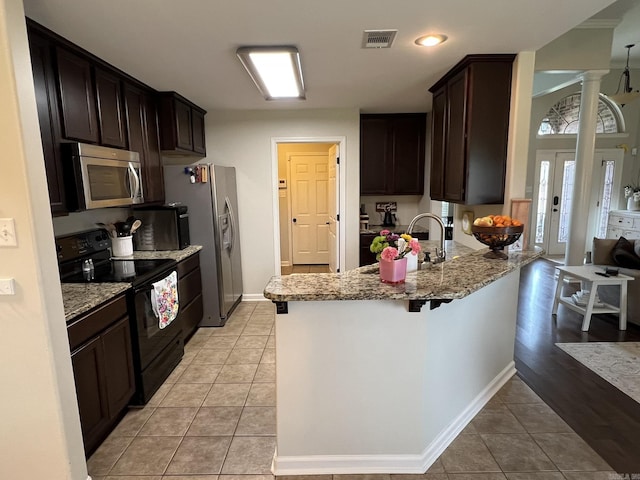 1056 Skyline Dr, Alexander, AR 72002 - kitchen with stainless steel appliances, a peninsula, a sink, dark brown cabinetry, and light tile patterned flooring
