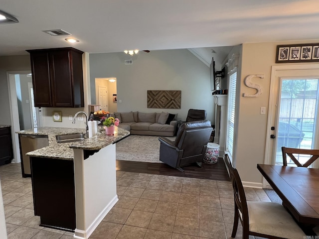 1056 Skyline Dr, Alexander, AR 72002 - kitchen featuring a sink, light tile patterned floors, dark brown cabinetry, vaulted ceiling, and light stone counters
