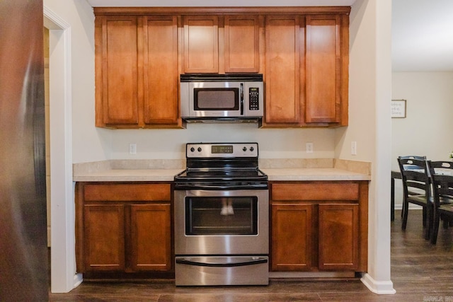 3961 Mountaincrest Cir, Alexander, AR 72002 - kitchen featuring appliances with stainless steel finishes, dark wood-type flooring, light countertops, and brown cabinetry