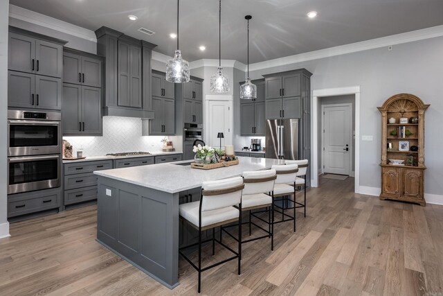 11 Haywood Ct, Little Rock, AR 72223 - kitchen with appliances with stainless steel finishes, gray cabinetry, ornamental molding, decorative backsplash, and a breakfast bar area