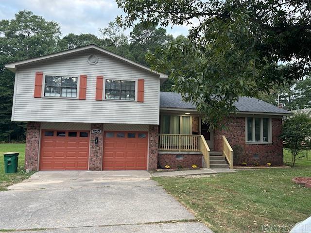 tri-level home with brick siding, an attached garage, driveway, and a front yard