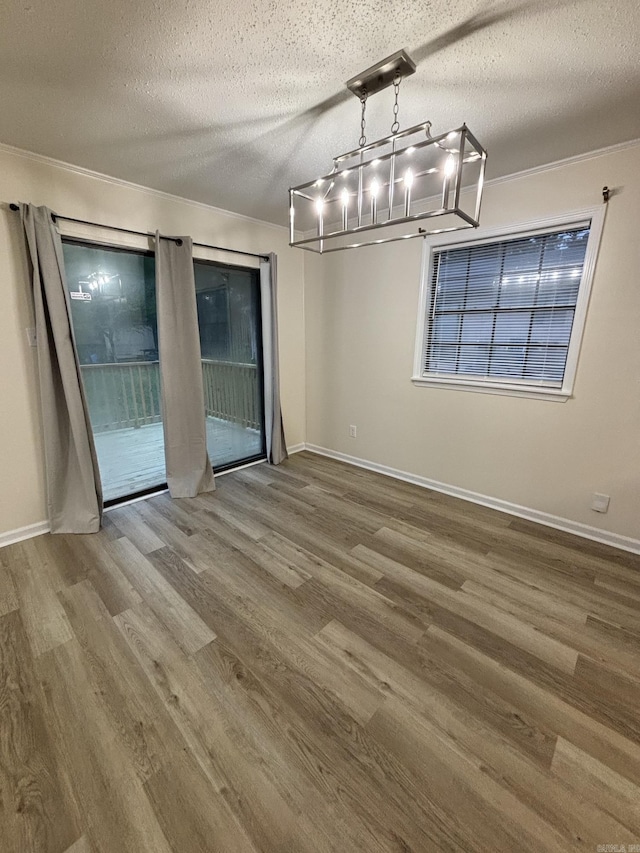unfurnished dining area featuring wood finished floors, a chandelier, baseboards, and a textured ceiling
