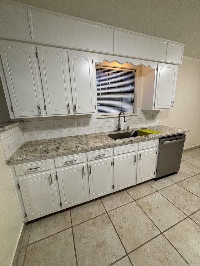 kitchen with stainless steel dishwasher, a sink, crown molding, white cabinets, and light tile patterned flooring