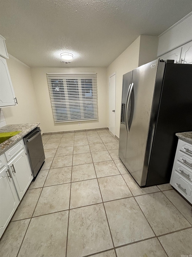 kitchen featuring stainless steel appliances, white cabinetry, a textured ceiling, and light tile patterned floors