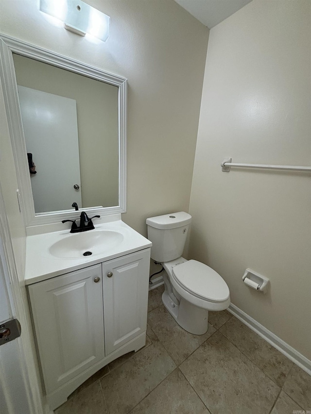 half bath with vanity, toilet, baseboards, and tile patterned flooring