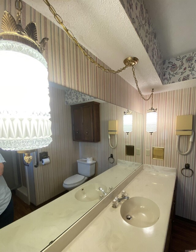 206 Beaconsfield Rd, Sherwood, AR 72120 - bathroom featuring wallpapered walls, wood finished floors, toilet, vanity, and a textured ceiling