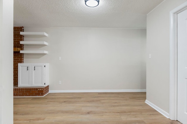 605 N W St, Morrilton, AR 72110 - empty room featuring light wood-style flooring, baseboards, and a textured ceiling