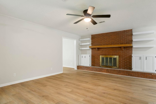 605 N W St, Morrilton, AR 72110 - unfurnished living room featuring ceiling fan, light wood-type flooring, baseboards, and a brick fireplace