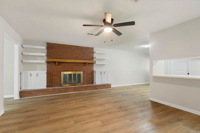 605 N W St, Morrilton, AR 72110 - unfurnished living room with a ceiling fan, light wood-type flooring, a brick fireplace, and baseboards