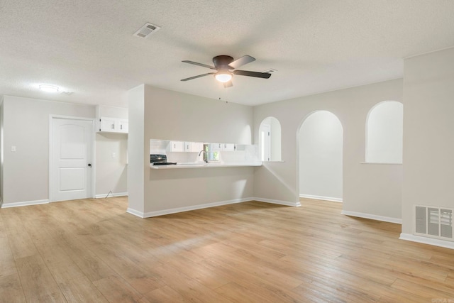 605 N W St, Morrilton, AR 72110 - unfurnished living room with ceiling fan, a textured ceiling, light wood-style floors, baseboards, and a sink