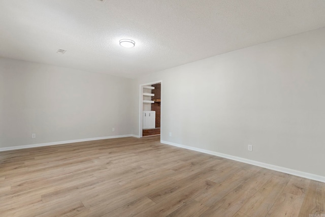 605 N W St, Morrilton, AR 72110 - unfurnished room featuring light wood-style floors, a textured ceiling, and baseboards