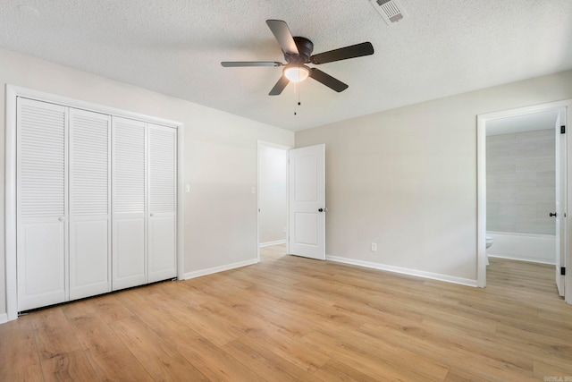 605 N W St, Morrilton, AR 72110 - unfurnished bedroom with light wood-type flooring, baseboards, ensuite bathroom, a closet, and a textured ceiling