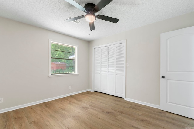 605 N W St, Morrilton, AR 72110 - unfurnished bedroom with light wood-style floors, a closet, baseboards, a ceiling fan, and a textured ceiling