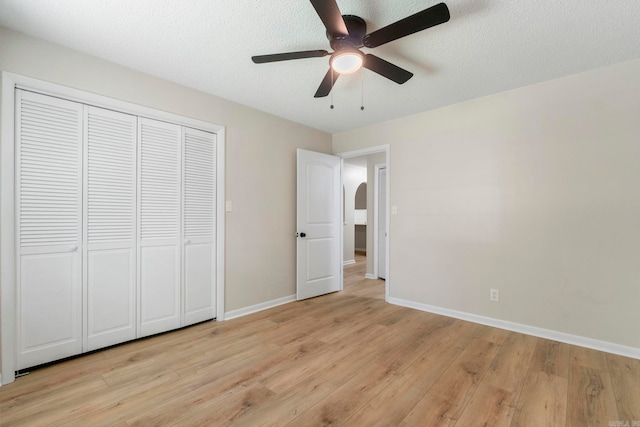 605 N W St, Morrilton, AR 72110 - unfurnished bedroom featuring light wood-style flooring, baseboards, a closet, arched walkways, and a ceiling fan