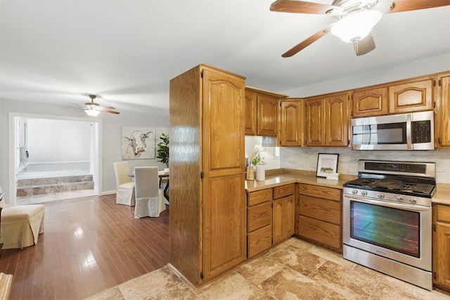 10626 Pineview Dr, Mabelvale, AR 72103 - kitchen featuring stainless steel appliances, ceiling fan, light countertops, and brown cabinetry