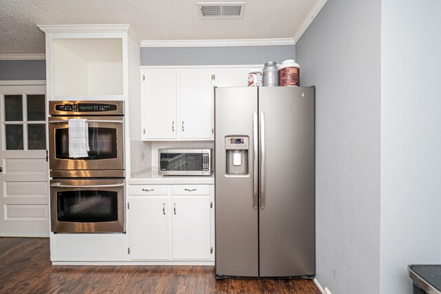 1211 Janwood St, El Dorado, AR 71730 - kitchen with appliances with stainless steel finishes, crown molding, white cabinets, dark wood-style floors, and a textured ceiling