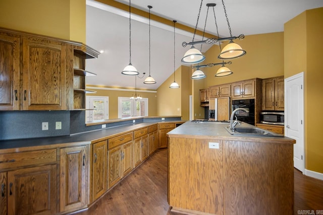 36 Brentwood Cv, Cabot, AR 72023 - kitchen featuring stainless steel microwave, dark wood finished floors, a kitchen island with sink, a sink, and decorative light fixtures
