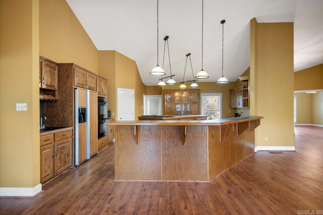 36 Brentwood Cv, Cabot, AR 72023 - kitchen with high vaulted ceiling, dark wood finished floors, a breakfast bar, paneled built in fridge, and a peninsula