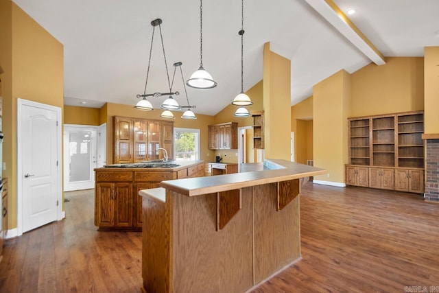 36 Brentwood Cv, Cabot, AR 72023 - kitchen featuring a kitchen island with sink, dark wood-style floors, a kitchen breakfast bar, brown cabinetry, and light countertops