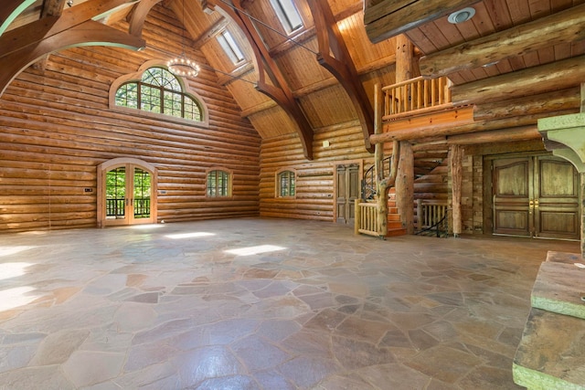 10836 Bray Rd, Elkins, AR 72727 - unfurnished living room with high vaulted ceiling, french doors, rustic walls, wood ceiling with exposed beams, and stone floors