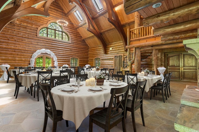 10836 Bray Rd, Elkins, AR 72727 - dining area featuring high vaulted ceiling, rustic walls, wood ceiling with exposed beams, stone tile floors, and a chandelier