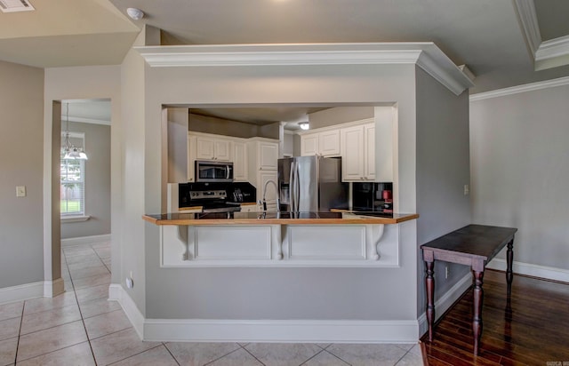 76 Woodridge Dr, Little Rock, AR 72204 - kitchen with appliances with stainless steel finishes, ornamental molding, baseboards, a breakfast bar, and a peninsula