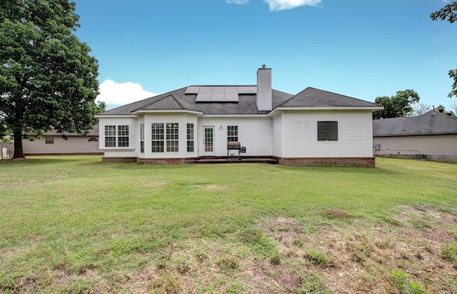 76 Woodridge Dr, Little Rock, AR 72204 - back of property with roof mounted solar panels, a chimney, a yard, and a shingled roof