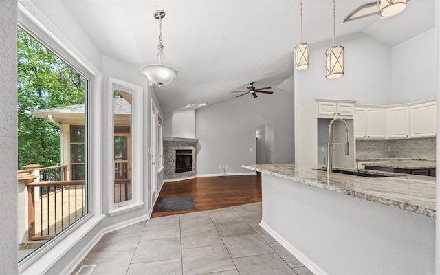 74 Medina Way, Hot Springs Village, AR 71909 - kitchen featuring a ceiling fan, a sink, light stone counters, a fireplace with raised hearth, and white cabinetry