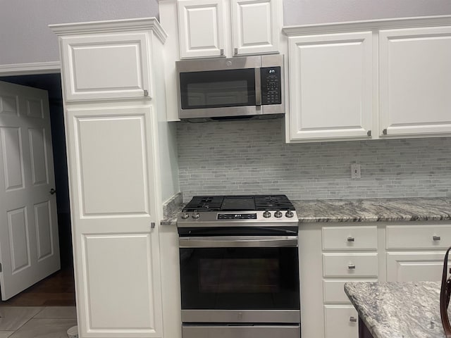 74 Medina Way, Hot Springs Village, AR 71909 - kitchen with stainless steel appliances, decorative backsplash, white cabinets, and light stone counters