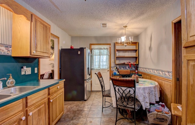 32 Bonnie Park Dr, Pine Bluff, AR 72601 - kitchen featuring freestanding refrigerator, a chandelier, a textured ceiling, a wainscoted wall, and a sink
