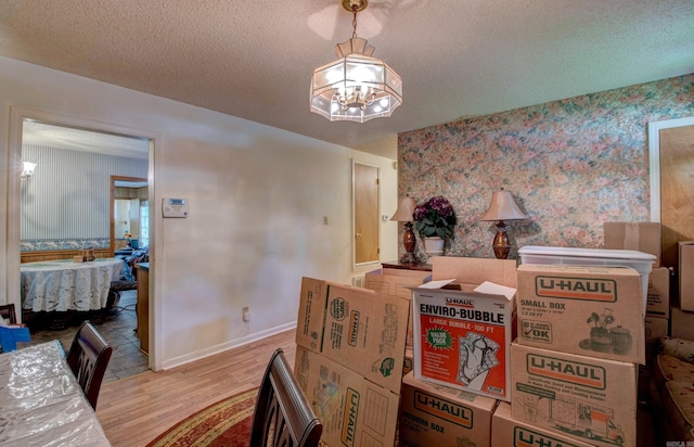32 Bonnie Park Dr, Pine Bluff, AR 72601 - dining area featuring wallpapered walls, light wood-style flooring, a textured ceiling, a chandelier, and baseboards