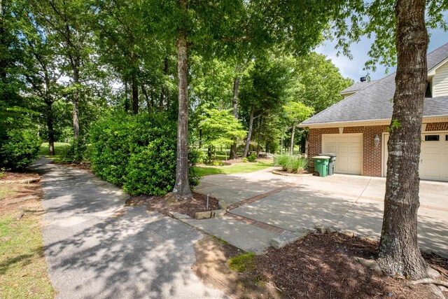 18 Chenal Cir, Little Rock, AR 72223 - view of home's exterior featuring roof with shingles, brick siding, driveway, view of wooded area, and an attached garage