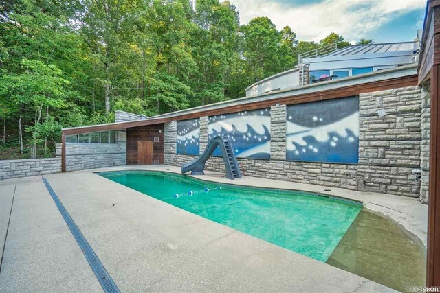 swimming pool with a water slide and a patio area