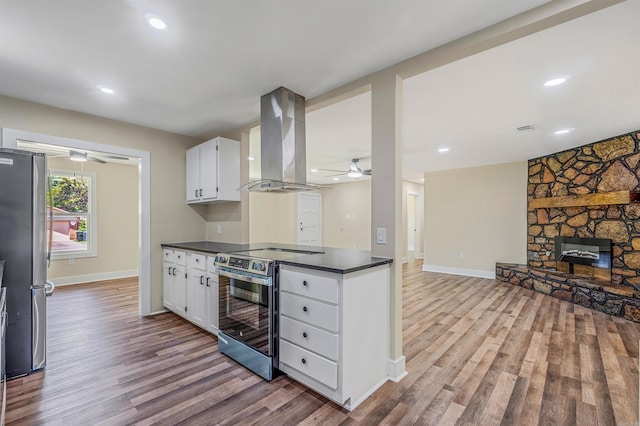 1907 Creekwood Dr, Conway, AR 72032 - kitchen with island exhaust hood, stainless steel appliances, a ceiling fan, dark countertops, and wood finished floors