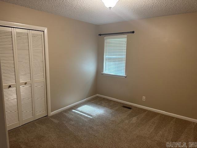 1 Rogers Dr, Morrilton, AR 72110 - unfurnished bedroom with a closet, carpet flooring, a textured ceiling, and baseboards