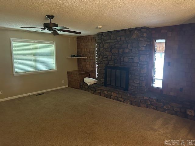 1 Rogers Dr, Morrilton, AR 72110 - unfurnished living room featuring a textured ceiling, carpet, ceiling fan, a stone fireplace, and baseboards