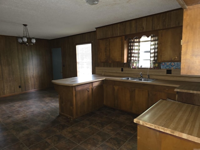85 Bailey Rd, Morrilton, AR 72110 - kitchen featuring a sink, a peninsula, wood walls, a chandelier, and a textured ceiling